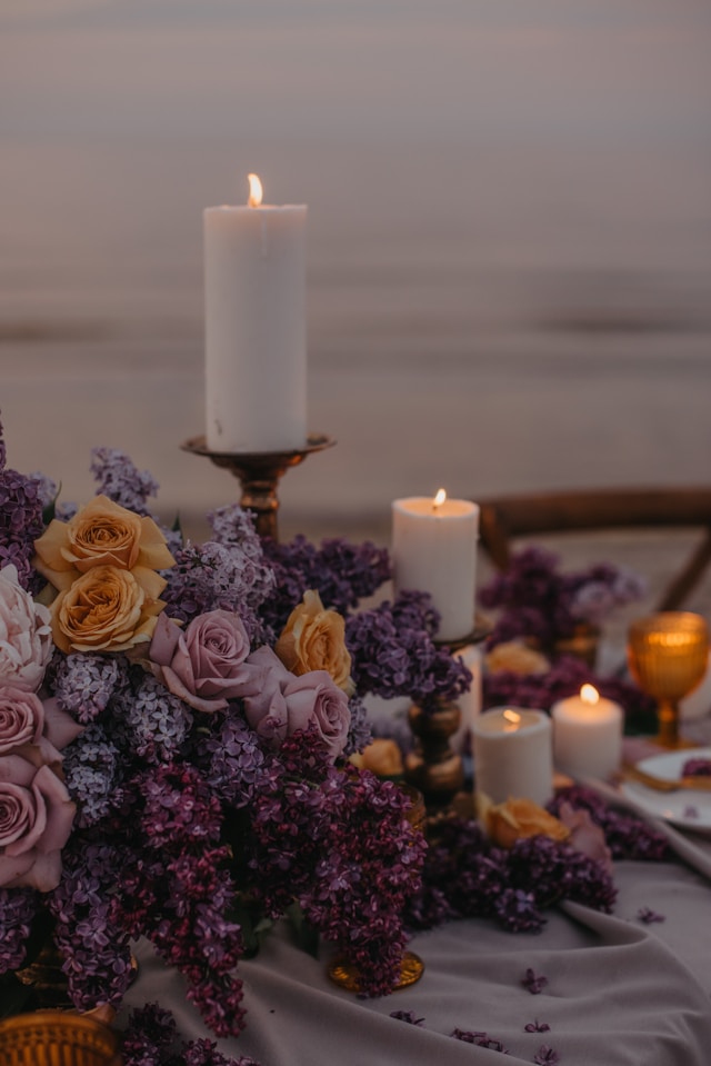 Photo of a table centerpiece of a candle and purple flowers