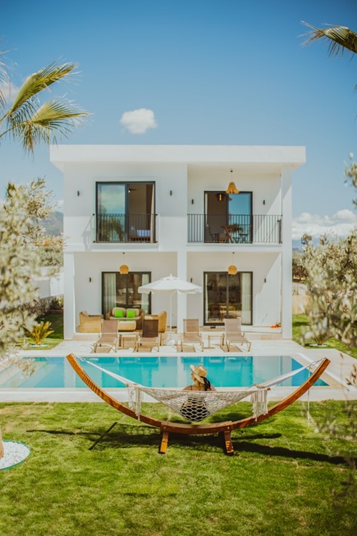 Photo of a two story villa with a pool and woman in a hammock.