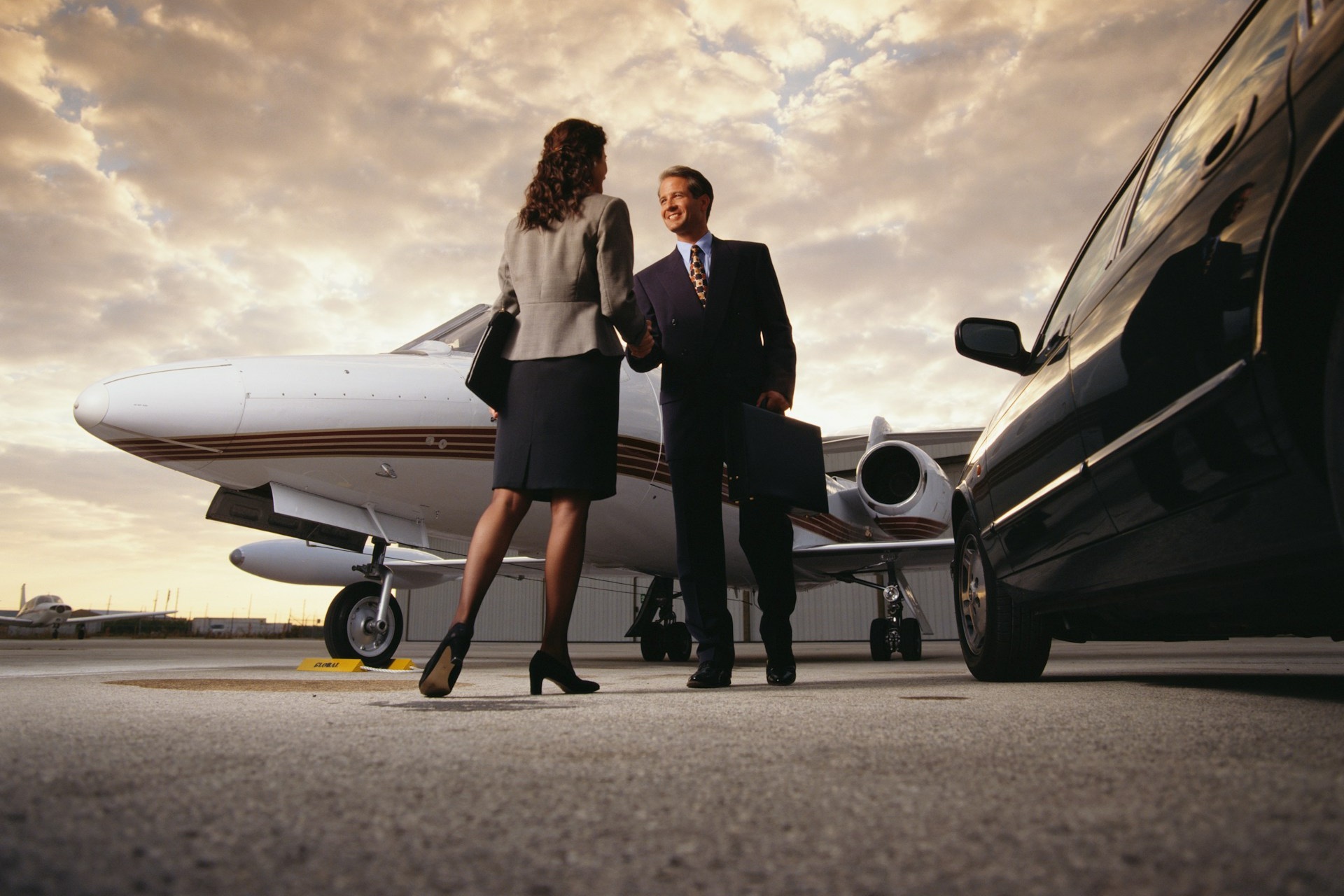 Photo of two people shaking hands in front of a private jet