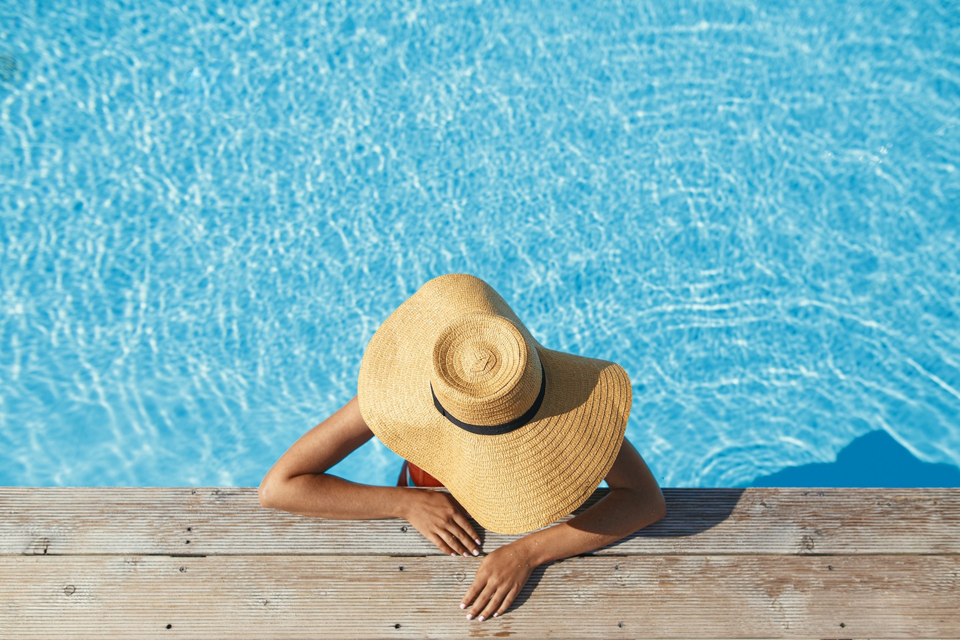 Photo of a person in a large brim hat in a pool as shot from above
