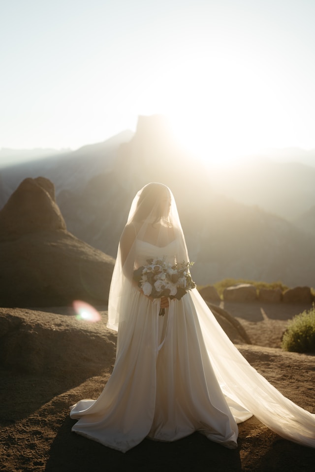 Photo of a bride in white backlight in front of a mountain backdrop